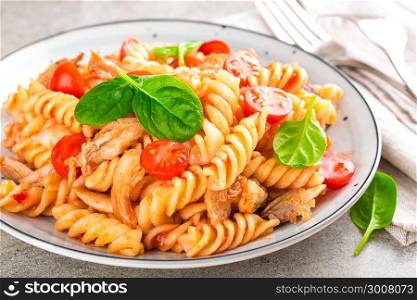 Pasta spirali stirred with fried pieces of chicken, cherry tomatoes and tomato sauce