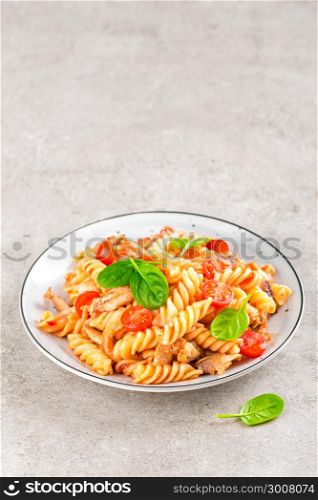 Pasta spirali stirred with fried pieces of chicken, cherry tomatoes and tomato sauce