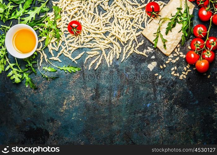 Pasta, tomatoes and ingredients for cooking on rustic background, top view, border. Italian food concept.