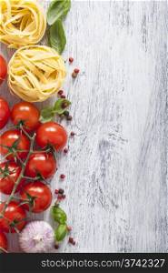 pasta tomatoes basil frame on white wooden background