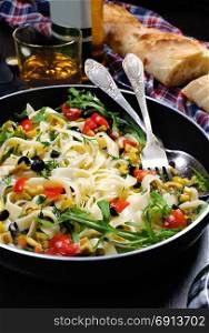 Pasta with crushed olives and cherry tomatoes, arugula. Vertical shot.