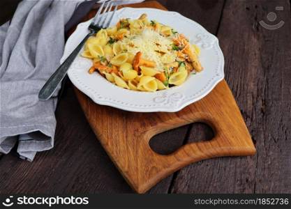 Pasta with organic chanterelles. portion of pasta with fried chanterelles in a creamy garlic sauce with cheese close-up on a plate on the table