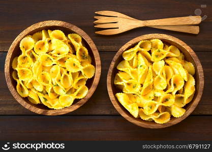 Pasta with pumpkin and parsley sauce served in wooden bowls, photographed overhead on dark wood with natural light (Selective Focus, Focus on the top of the dish)