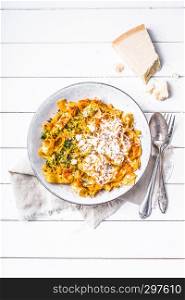 pasta with red pesto sauce sprinkled with fresh parmesan and herbs