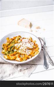 pasta with red pesto sauce sprinkled with fresh parmesan and herbs