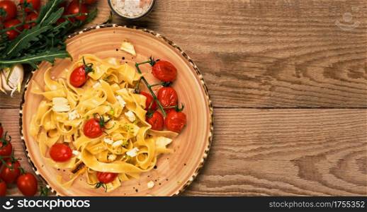Pasta with sauteed cheese slices, grilled cherry tomatoes and olive oil. Layout on an old wooden table, horizontal frame with copy space. Ingredients for spaghetti on the table. Vegetarian pasta idea