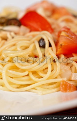 Pasta with tomato, black olives, capers and greens