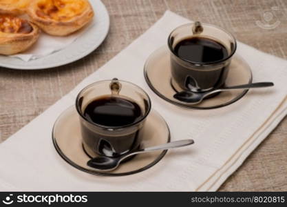 Pasteis de Nata or Portuguese Custard Tarts with black coffee on wooden table.