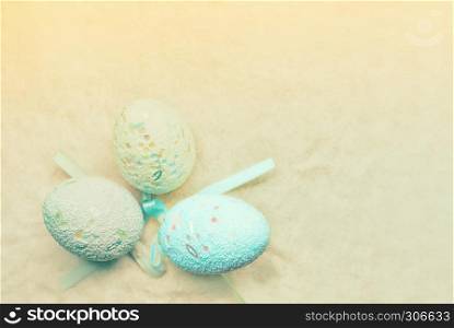 Pastel blurred background - decorative Easter eggs on beige sand. Soft focus, space for copy.. Pastel Easter Eggs Background