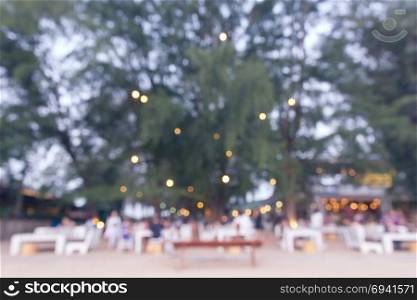 Pastel blurred background of beach restaurant with tree and seat.