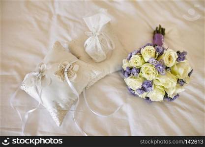 Pastel bouquet with roses and violet flower decoration for the bride and cushion for wedding rings on the bed