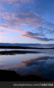 Pastel clouds reflecting in Loch Dunvegan in Scotland.