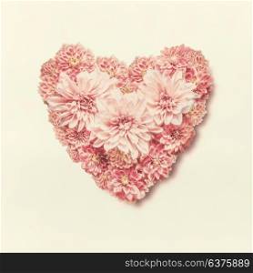 Pastel color heart made of lovely pink flowers, top view. Love, wedding or Valentines day concept. Layout for greeting card