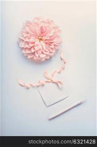 Pastel color mock up with cream pink flower , blank paper card with ribbon and point pen on light blue desktop background, top view. Layout of greeting card for Mothers day, wedding or happy event