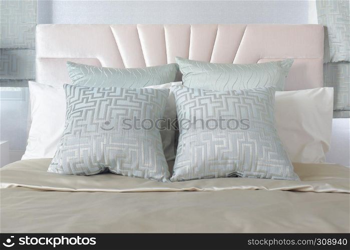 Pastel color of pillows setting on bed with satin bedding style