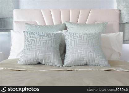 Pastel color of pillows setting on bed with satin bedding style