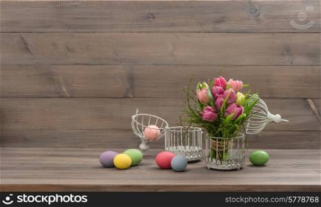 pastel colored tulip flowers and easter eggs over wooden background