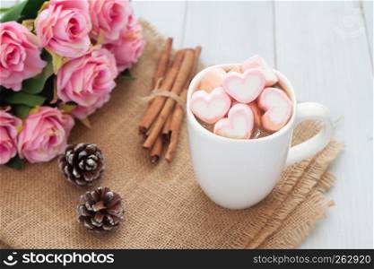 Pastel heart marshmallows on hot chocolate cup with pink roses. Love lifestyle or Valentine's Day concept