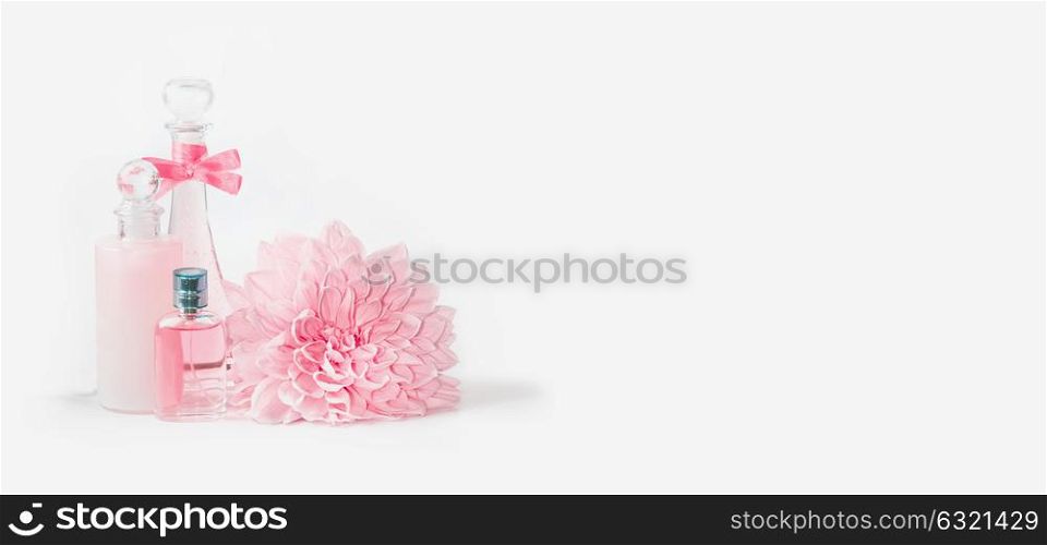 Pastel pink cosmetic bottles mock up setting with flower on white background, front view, banner. Layout for skin care, wellness or spa and beauty concept