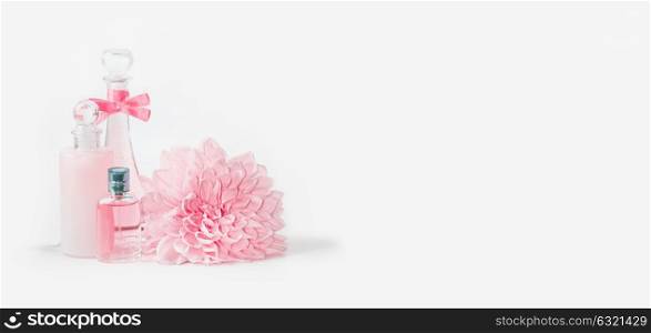 Pastel pink cosmetic bottles mock up setting with flower on white background, front view, banner. Layout for skin care, wellness or spa and beauty concept