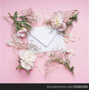 Pastel pink flowers around White envelop , floral arrangement , top view