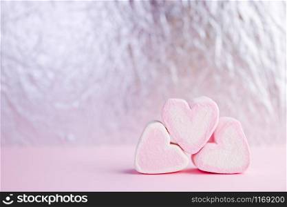 Pastel valentine background made of marshmallows souffle in the form of hearts on a pink and silver background. Valentine&rsquo;s Day concept with copy space.. Pastel valentine background made of marshmallows souffle in the form of hearts on a pink and silver background. Valentine&rsquo;s Day concept with copy space