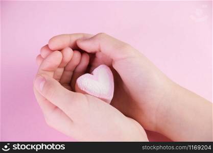 Pastel valentine background made of marshmallows souffle in the form of hearts on a pink background in hands. Valentine&rsquo;s Day concept with copy space.. Pastel valentine background made of marshmallows souffle in the form of hearts on a pink background in hands. Valentine&rsquo;s Day concept with copy space