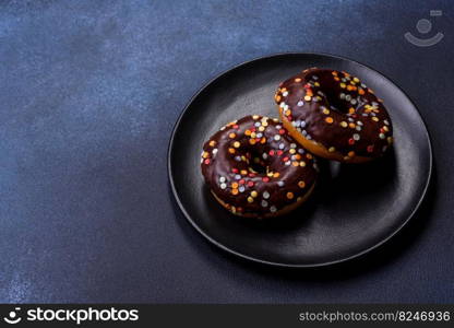 Pastries concept. Donuts with chocolate glaze with sprinkles, on a dark concrete table. Sweet food for a breakfast. Pastries concept. Donuts with chocolate glaze with sprinkles, on a dark concrete table