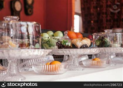 Pastry bar and assorted puff pastries, fruits on luxurious glass pedestal tray in vintage decor bakery cafe