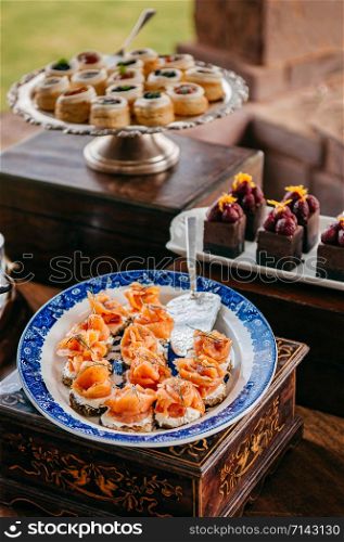 Pastry bar assorted pastries, smoked salmon with cream cheese and dessert chocolate cake in beautiful ceramic plate and tray