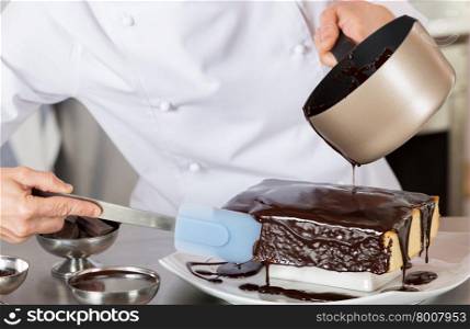 Pastry chef in the kitchen decorating a cake of chocolate