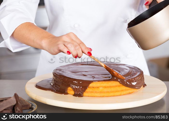 Pastry chef in the kitchen decorating a cake of chocolate