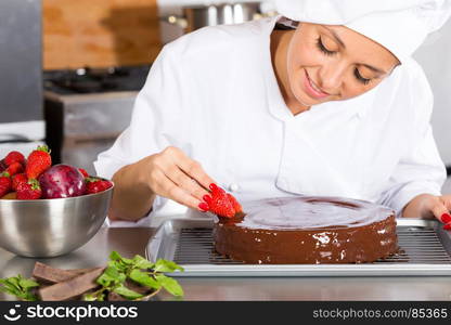 Pastry chef in the kitchen decorating a cake of chocolate