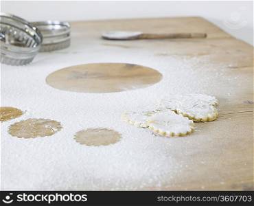 Pastry cutters, cookies and flour scattered on table, close up