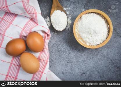 Pastry flour on wooden bowl on gray background, top view / homemade flour eggs cooking ingredients on kitchen table