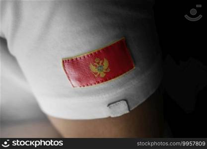 Patch of the national flag of the Montenegro on a white t-shirt.. Patch of the national flag of the Montenegro on a white t-shirt