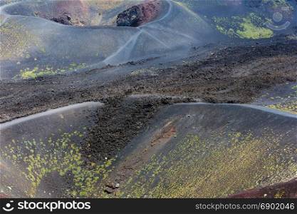 Path between summer Etna volcano mountain craters, Sicily, Italy. People unrecognizable.