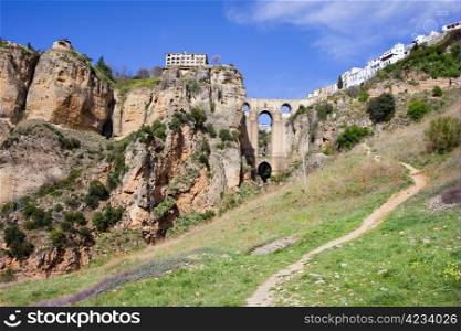Path through a meadow leading to the New Bridge (Spanish: Puente Nuevo) from 18th century in the town of Ronda, Andalucia, Spain.