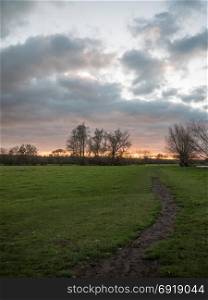 path through open flat plain country trees sky sunset dramatic ; essex; england; ukpath through open flat plain country trees sky sunset dramatic