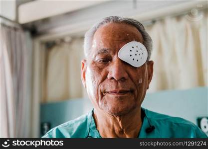 patient covering eye with protective shield & medical plaster after eyes cataract surgery in hospital