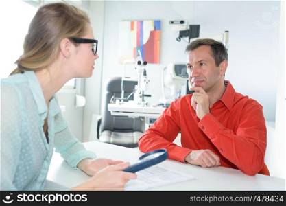 patient holding magnifying glass to read text during ophthalmologist consultation