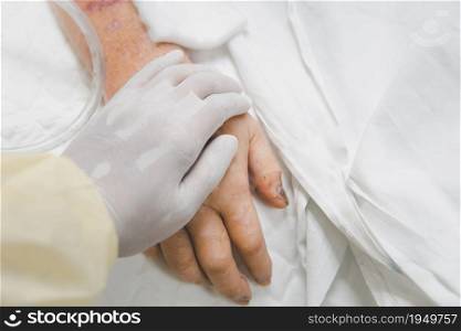 Patient in the hospital with saline intravenous and relatives patient hand holding a elderly patient hand. Patient in the hospital and holding a hand