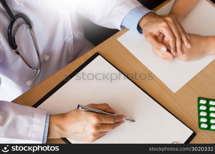 patient listening intently to a male doctor explaining patient symptoms or asking a question as they discuss paperwork together in a consultation.