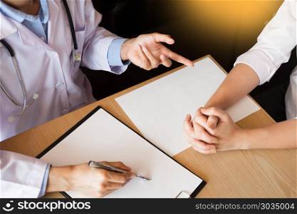 patient listening intently to a male doctor explaining patient symptoms or asking a question as they discuss paperwork together in a consultation.. patient listening intently to a male doctor explaining patient s