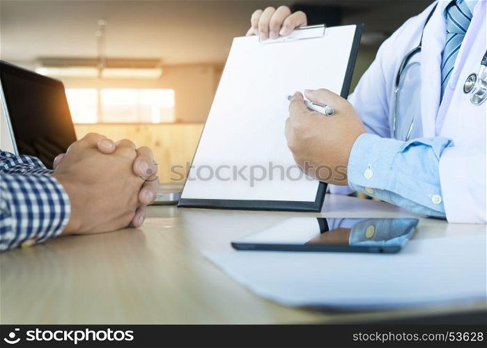 patient listening intently to a male doctor explaining patient symptoms or asking a question as they discuss paperwork together in a consultation.