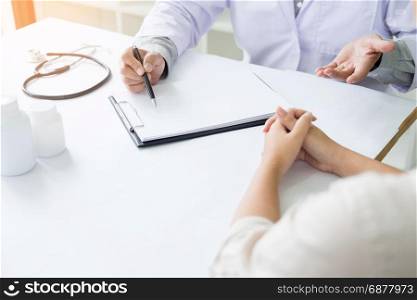 patient listening intently to a male doctor explaining patient symptoms or asking a question as they discuss paperwork together in a consultation.