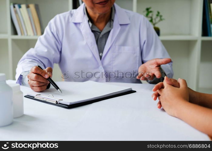 patient listening intently to a male doctor explaining patient symptoms or asking a question as they discuss paperwork together in a consultation