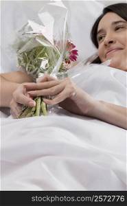 Patient lying on the bed and holding a bouquet of flowers