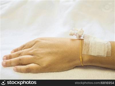 Patient's hand with medicine drip injection, lady on a bed in a hospital
