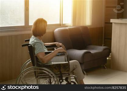 Patient sitting alone on wheelchair looking out at hospital or home care window with hope.